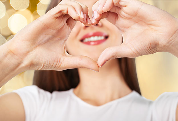 Woman making heart with hands and smiling | Walbridge Dental
