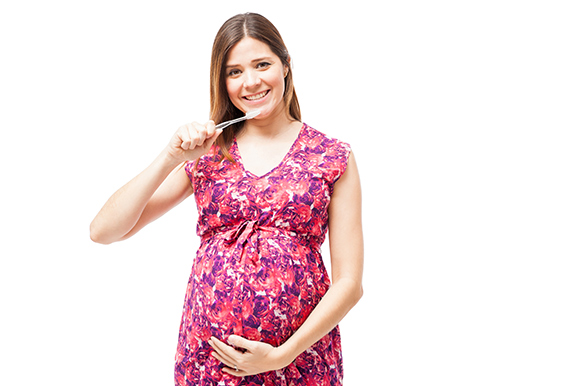 Smiling pregnant woman holding a toothbrush.