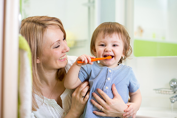 Mother teaching her young child to brush their teeth.