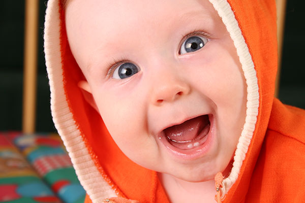 Excited baby smiling with new baby teeth. 