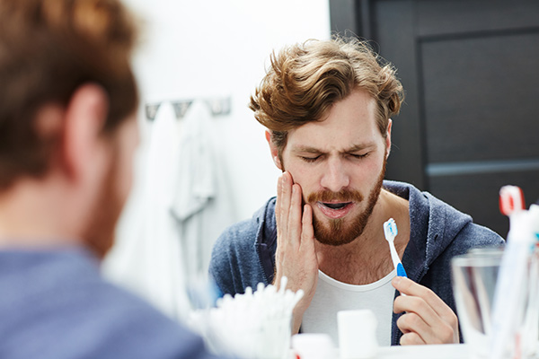 Man with sensitive gums brushing his teeth.