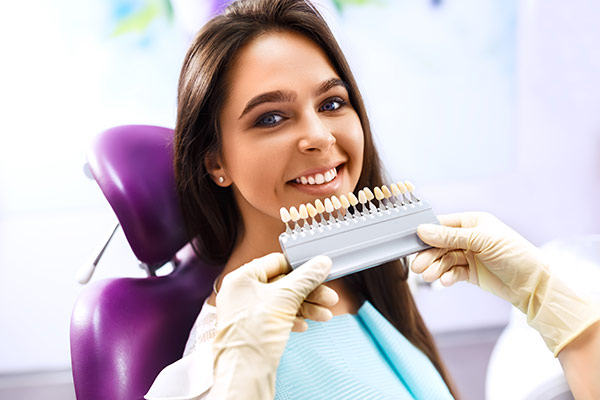 A woman at the dentist being color-matched for veneers
