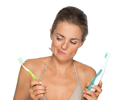Woman holding an electric and manual toothbrush