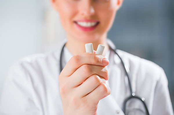 A dentist holding up pieces of chewing gum.