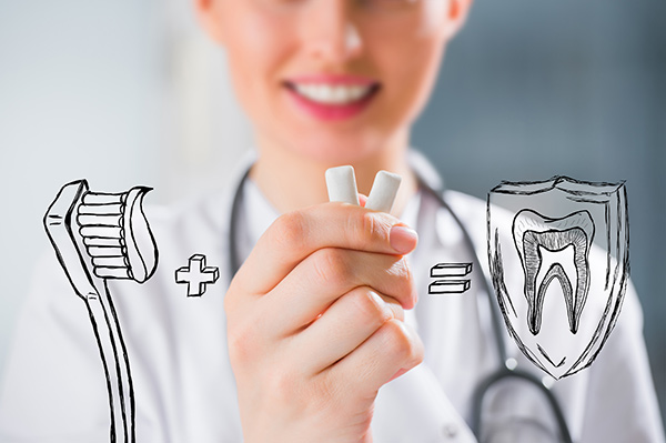 A dentist holding xylitol gum with images of a toothbrush plus gum equaling protected teeth.