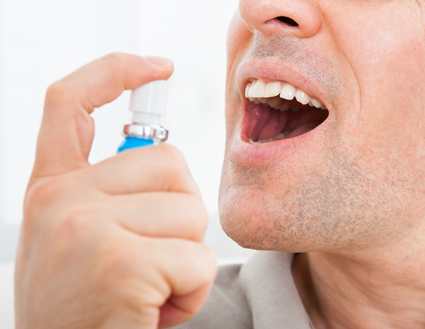 A man using mouth spray to get fresh breath