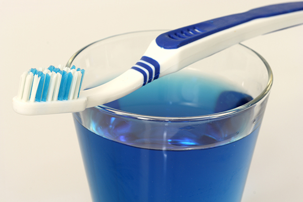 Dental fluoride in a cup beneath a toothbrush