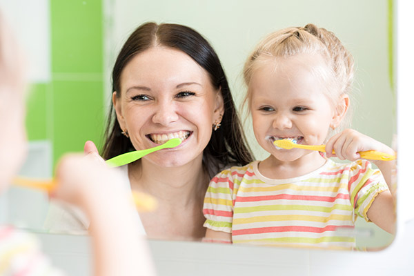 A mother and daughter brushing their teeth together