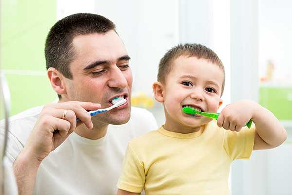 A father and son brushing their teeth together