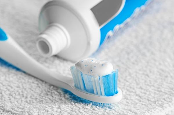 A toothbrush laying on a towel with fluoride toothpaste on it.