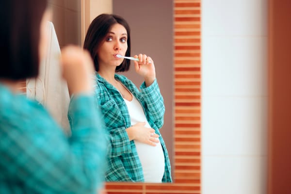 A pregnant woman using a toothbrush to avoid pregnancy gingivitis