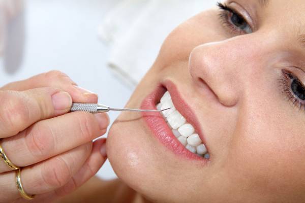 A woman at the dentist undergoing dental scaling to clean plaque from her teeth